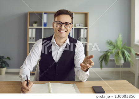 Happy smiling young business man having online video call sitting in office. Happy smiling young business man having online video call sitting in office. 130003850