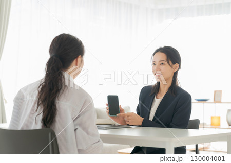 リビングでスマホの説明をするビジネスウーマン リビングでスマホの説明をするビジネスウーマン 130004001
