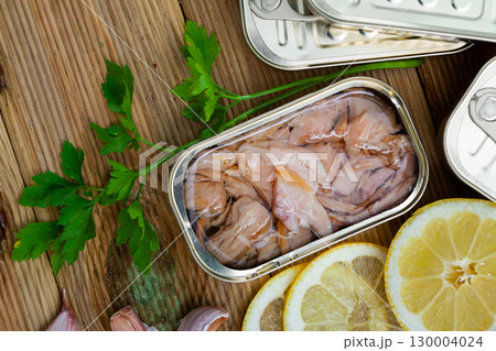 Canned tuna in open tin can with greens and lemon 130004024