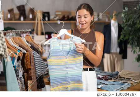 Girl customer choose blouse in store, and buyer carefully examines product. Girl customer choose blouse in store, and buyer carefully examines product. 130004267