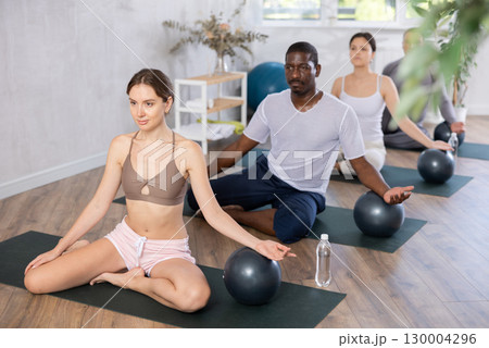Young woman doing pilates in group in studio Young woman doing pilates in group in studio 130004296