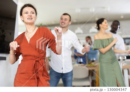 Dance moves of men and woman of different nationalities at fun holiday party at home Dance moves of men and woman of different nationalities at fun holiday party at home 130004347