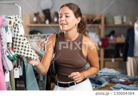 Girl customer choose scarf in store, and buyer carefully examines product. Girl customer choose scarf in store, and buyer carefully examines product. 130004364