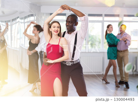 Woman with African man dancing waltz in couple during lesson at studio 130004493
