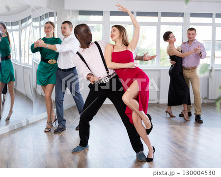Woman with African man dancing waltz in couple during lesson at studio 130004530