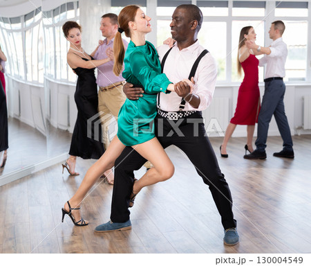 Dance training in group - men and women of different nationalities and different ages dance tango or bachata in dance studio Dance training in group - men and women of different nationalities and different ages dance tango or bachata in dance studio 130004549