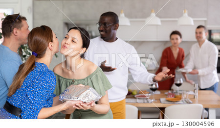 Friends and couples greet each other and give gifts before the festive dinner at house party 130004596