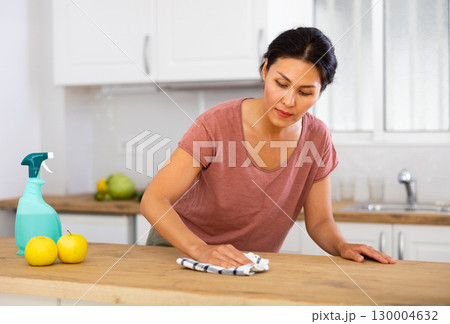Woman cleaning table with rag at home Woman cleaning table with rag at home 130004632