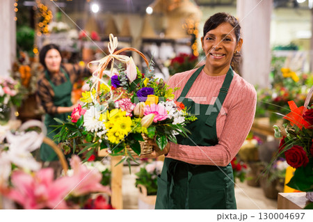 Smiling latin american florist woman stands with flowers Smiling latin american florist woman stands with flowers 130004697