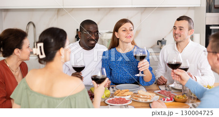Happy adult friends at the festive table discussing news and drinking red wine 130004725