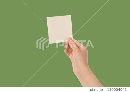 Hand holds untitled paper against a green backdrop Hand holds untitled paper against a green backdrop 130004941