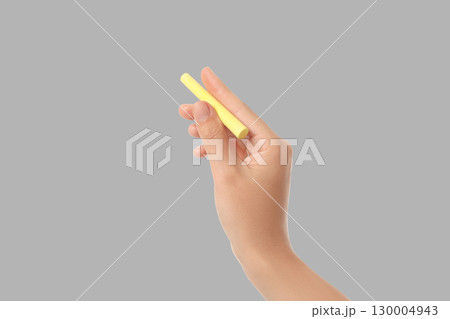 A hand grips a yellow chalk piece in preparation for creativity 130004943