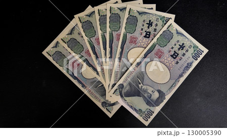 黒バックに扇状に並べた千円札 130005390