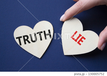 Truth or Lie symbol. Concept word Truth or Lie on wooden hearts. Businessman hand. Beautiful deep blue background. Business and Truth or Lie concept. Copy space 130005752