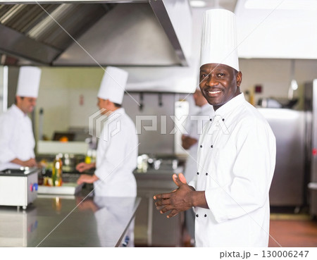 AI generated A professional chef stands at the frame edge gesturing welcomingly toward a well-equipped kitchen The scene conveys culinary expertise hospitality and premium dining 130006247