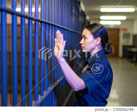 AI generated A uniformed police officer stands at the frame edge gesturing authoritatively toward a jail cell in a police station The scene conveys law enforcement security and justice system themes 130006248