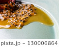 皿の上の半分に切ったパッションフルーツからこぼれ出る果実と果汁 130006864