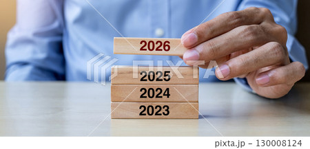 Businessman hand pulling 2026 wooden building blocks on table background. Business planning, Risk Management, Resolution, strategy, solution, goal, New Year New You and happy holiday concepts Businessman hand pulling 2026 wooden building blocks on table background. Business planning, Risk Management, Resolution, strategy, solution, goal, New Year New You and happy holiday concepts 130008124