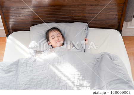 ベッドでぐっすりと寝る小さな女の子 ベッドでぐっすりと寝る小さな女の子 130009002