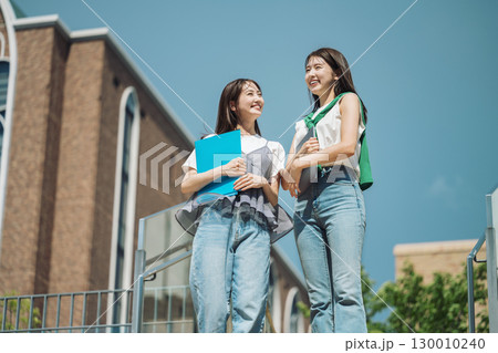 友達と楽しく話しながら校内を歩く女子大生 130010240
