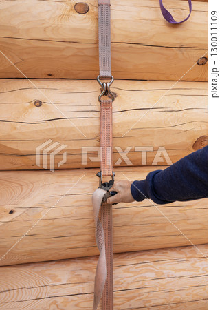 The construction site of a wooden house. Traditional log cabin built from wood logs on sunny summer day. Cottage house design 130011109