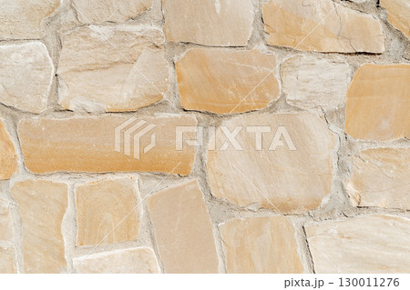 Antique ancient stone wall masonry texture background. Old wall made of beige stone blocks  130011276
