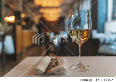 Glass of White Wine on Restaurant Table. Elegant Dining Atmosphere Glass of White Wine on Restaurant Table. Elegant Dining Atmosphere 130011302