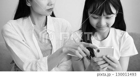 スマホに夢中になる娘に注意する母親のイメージ スマホに夢中になる娘に注意する母親のイメージ 130011493