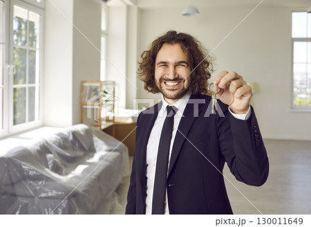 Portrait of a young happy smiling man with keys in his hands looking at camera in new house. Portrait of a young happy smiling man with keys in his hands looking at camera in new house. 130011649