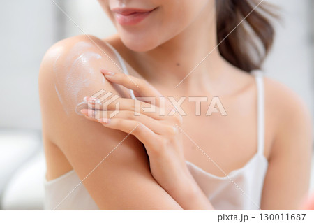 Closeup hands young woman applying cream or lotion while looking mirror in living room at home. 130011687