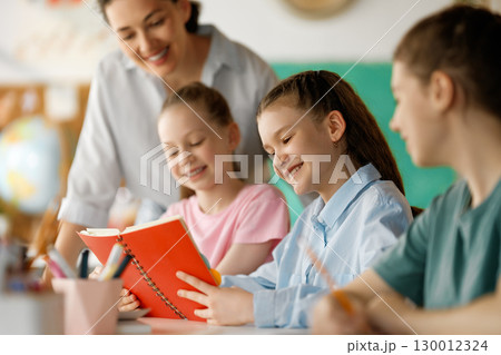 Happy kids and teacher at school 130012324