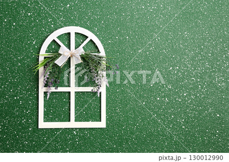 Little decorative wooden window with lace bow and flower on green stucco wall. Home sweet home style background. Charming wood window adorned with lace-trimmed bow and flower. Copy space for text 130012990