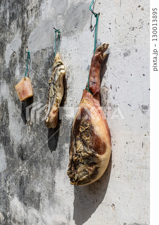 Traditional Anhui chunk of preserved meat being hung on wall under sun in drying process. Traditional Anhui chunk of preserved meat being hung on wall under sun in drying process. 130013895
