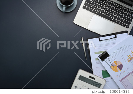 Top view of office desk with laptop, calculator, financial reports, and coffee cup on desk Top view of office desk with laptop, calculator, financial reports, and coffee cup on desk 130014552