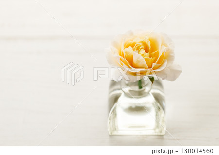 Yellow beautiful rose in glass vase on wooden table. Selective focus. Yellow beautiful rose in glass vase on wooden table. Selective focus. 130014560
