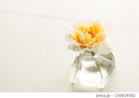 Yellow beautiful rose in glass vase on wooden table. Selective focus. Yellow beautiful rose in glass vase on wooden table. Selective focus. 130014562