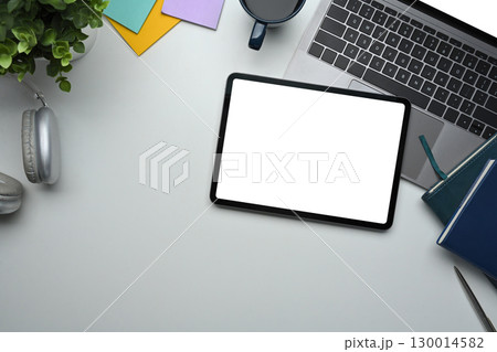 Top view of tablet with blank screen on desk alongside laptop, coffee cup, and notebooks Top view of tablet with blank screen on desk alongside laptop, coffee cup, and notebooks 130014582