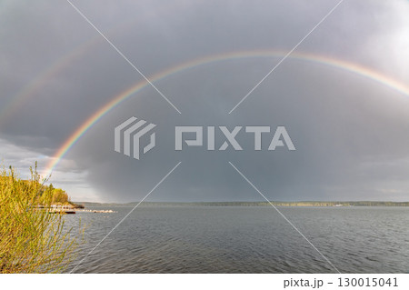 Rainbow over Blue lake with cloudy sky 130015041