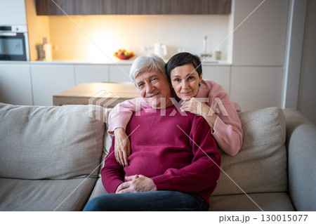 Happy senior husband and wife hugging on couch looking at camera. Married couple spend time together Happy senior husband and wife hugging on couch looking at camera. Married couple spend time together 130015077