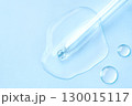 Drop of cosmetics and a pipette on a blue background. A product for skin, face or hair care. 130015117