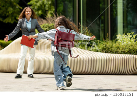 Joyful little girl running with open arms towards her mother 130015151