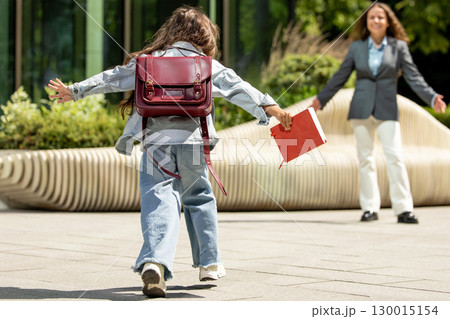 Female child joyfully running toward her mother in soft daylight 130015154