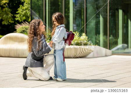 Confident mother with her daughter wearing backpack and folder 130015163