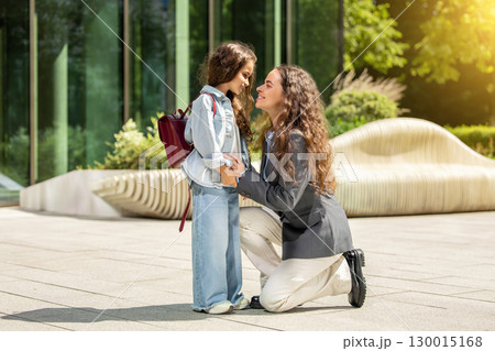 Schoolgirl and adult woman together outside office building Schoolgirl and adult woman together outside office building 130015168
