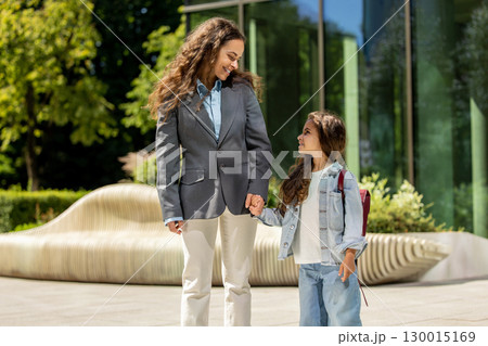 Mother and daughter posing happily near sleek urban bench and glass building Mother and daughter posing happily near sleek urban bench and glass building 130015169