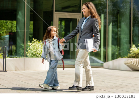 Working mom and child walking together after school in urban setting Working mom and child walking together after school in urban setting 130015193
