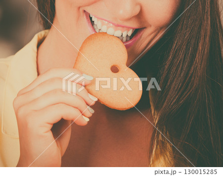 girl eating biting gingerbread cookie. 130015285