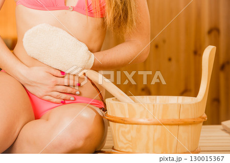 Closeup of woman in sauna with exfoliating glove. 130015367