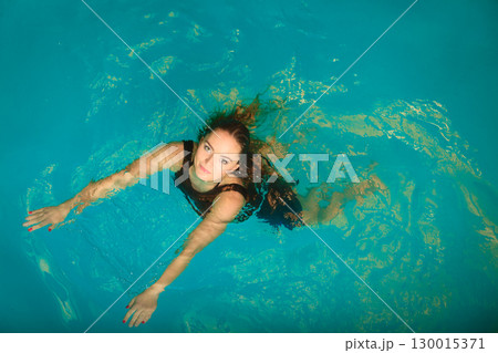 Woman floating relaxing in swimming pool water. Woman floating relaxing in swimming pool water. 130015371