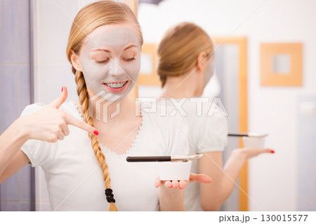 Woman applying with brush clay mud mask to her face 130015577
